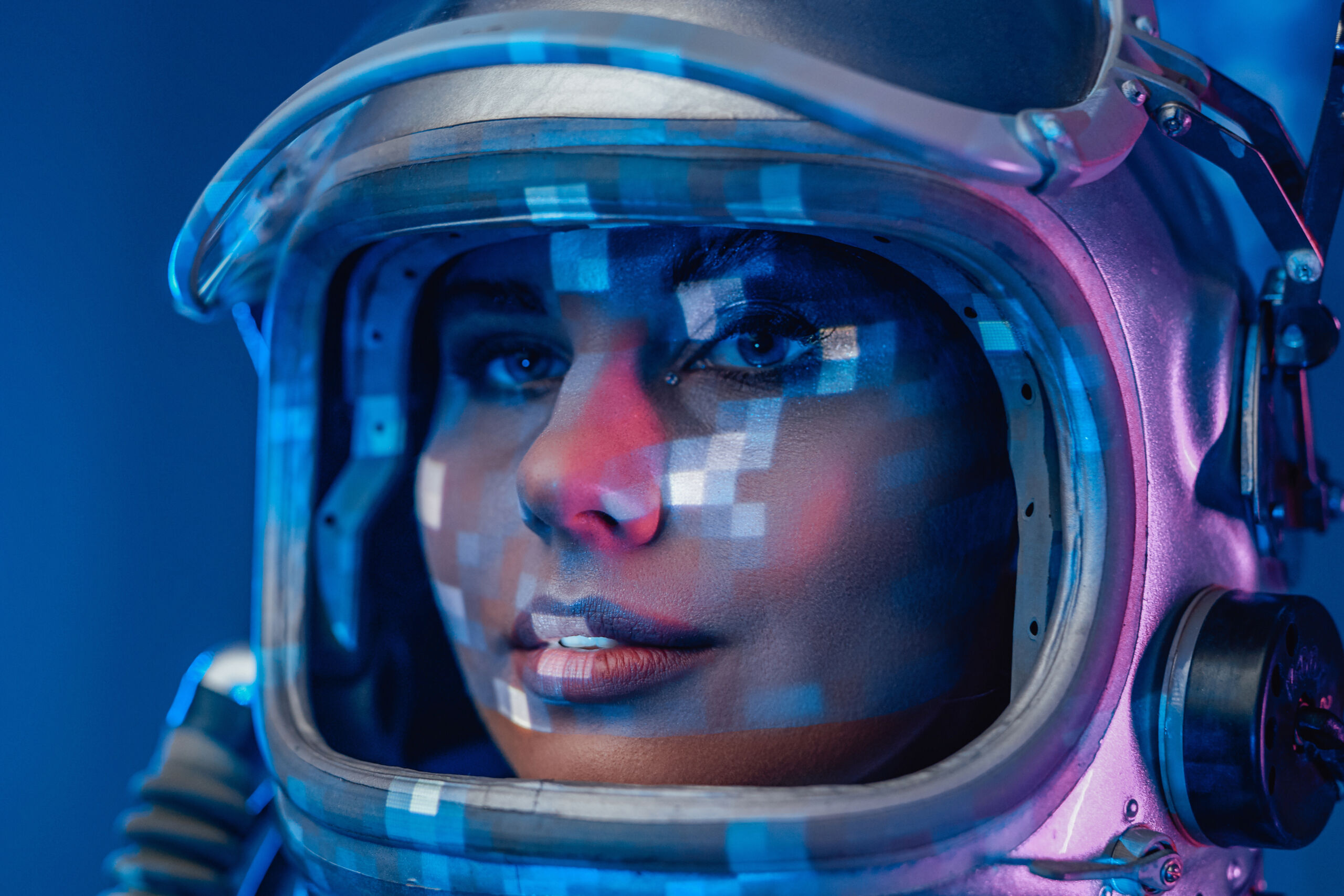 Closeup studio shot of woman astronaut in space helmet under colourful illumination.